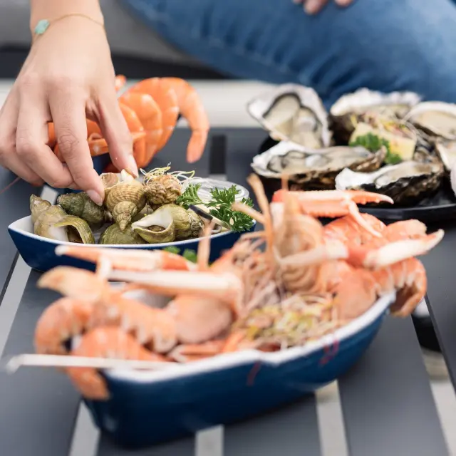 mainq ui bedient sich an den Langustinen und Austern, die auf einem Tisch präsentiert werden.